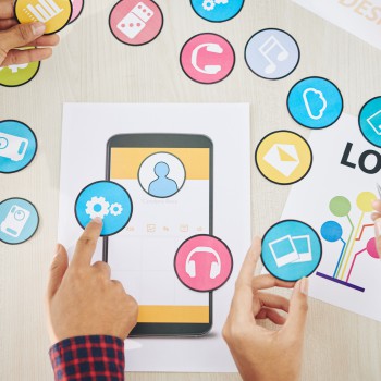 Designers discussing set of icons for mobile application, view from above