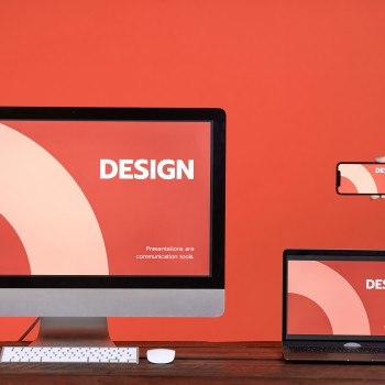 Web design concept with hand holding smartphone, computer and laptop at wooden table over coral background, copy space